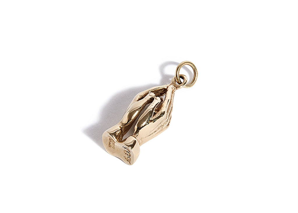 Gold pendant shaped like a pair of clasped hands on a white background